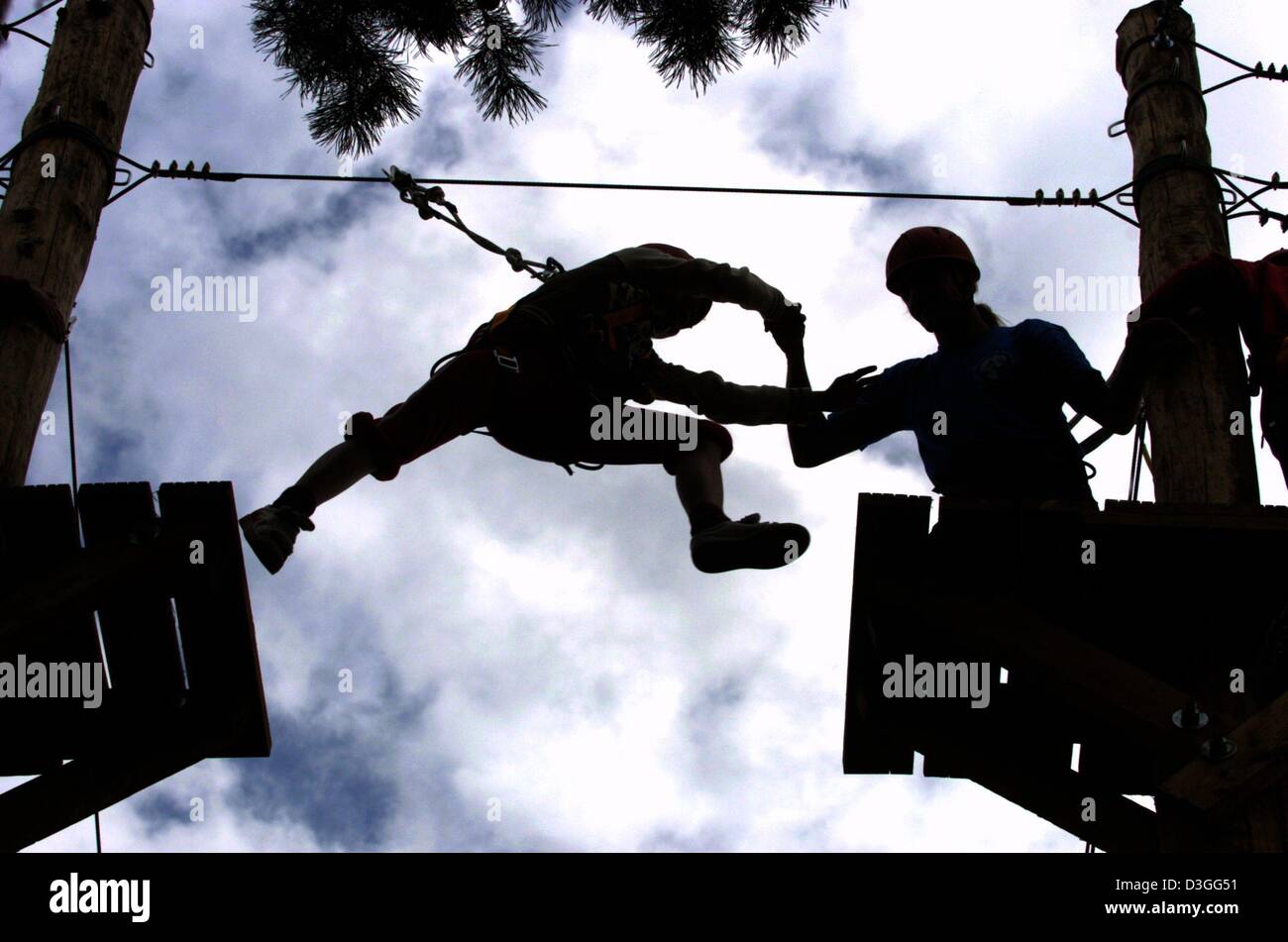 (Dpa) - 12 Meter über dem Boden springt ein Kind auf einer Plattform umgeben von Drahtseilen und schwingende Bretter im Highwire Garten in Spremberg, Deutschland, 26. Juli 2004. Trainer Anweisungen geben und helfen Besuchern mit Sicherheit Seile. Stockfoto