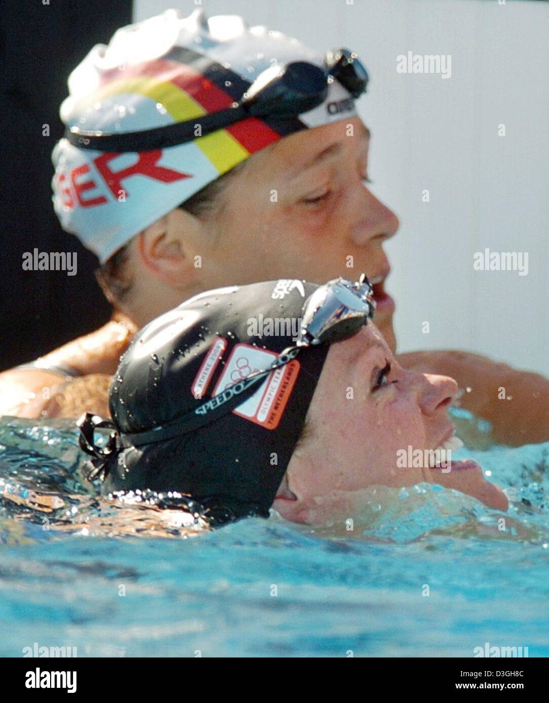 (Dpa) - kümmert sich um deutsche Schwimmerin Sandra Voelker (wieder) enttäuscht nicht die Qualifikation für das Halbfinale in ihre Frauen 50m Freestyle Hitze an die 2004 Olympic Aquatic Centre in Athen, Griechenland, 20. August 2004, während der niederländischen Weltrekordhalter Inge de Bruijn lächelt. De Bruijn fuhr die schnellste Gesamtzeit. Stockfoto