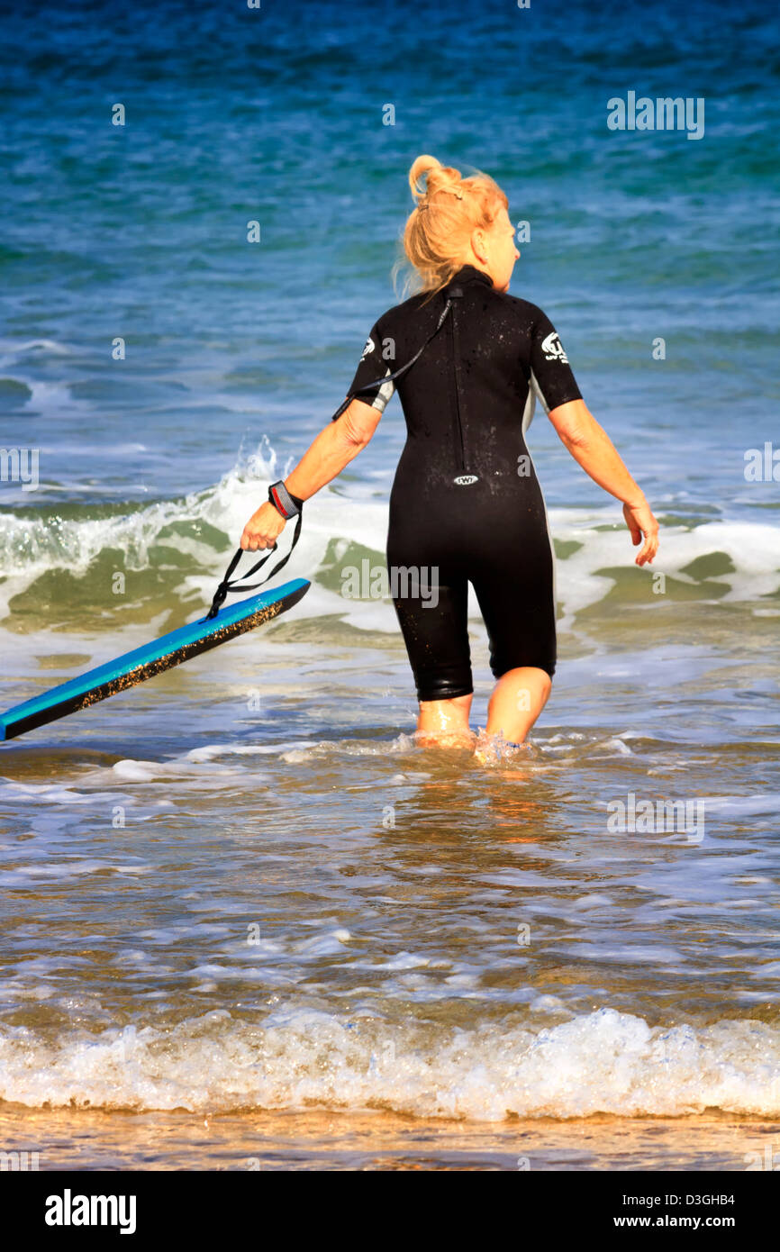 Reife Frau mit einem Surfen body Board, Harlyn Bay, Cornwall, England Stockfoto