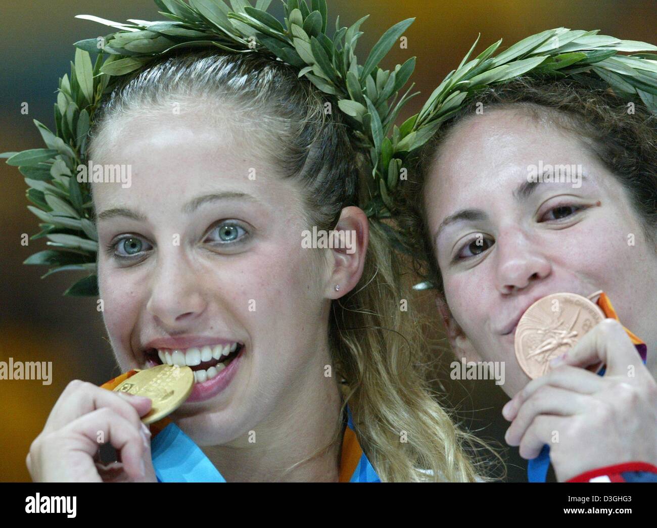 (Dpa) - stellt Mariel Zagunis (L) aus den USA mit ihren Kollegen ihre Landsfrau Sada Jacobson, die Bronze und beißt in ihre Goldmedaille gewann, nachdem er die Frauen einzelne Sabre Goldmedaille Kampf bei den Olympischen Spielen 2004 in Athen, Griechenland, 17. August 2004.  Die einzelnen Sabre Disziplin Premiere für das erste Mal bei den Olympischen Spielen und Zagunis die erste ist jemals US Fechter, wi Stockfoto