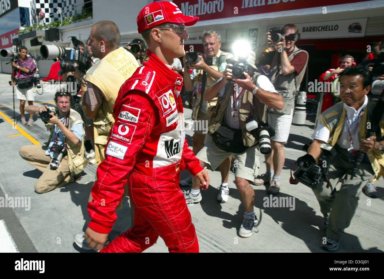 (Dpa) - deutsche Formel 1 pilot Michael Schumacher (C) geht vorbei an einer Gruppe von Fotografen in Richtung seiner Grube auf dem Hungaroring Rennstrecke in Budapest, Ungarn, 13. August 2004. Schumacher verließ die Grube in seinem Rennwagen zum ersten Mal 35 Minuten nach Beginn des freien Trainings. Formel 1 Grand Prix von Ungarn wird am Sonntag, 15. August im Gange sein. Stockfoto