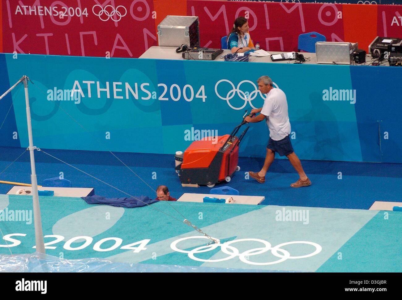 (Dpa) - ein Helfer hoovers Blume zwischen den Trainingseinheiten der Turner in der Oaka Hall in Athen, Griechenland, 9. August 2004. Die Olympischen Spiele 2004 werden mit der Eröffnungsfeier am 13 August gestartet werden. Stockfoto