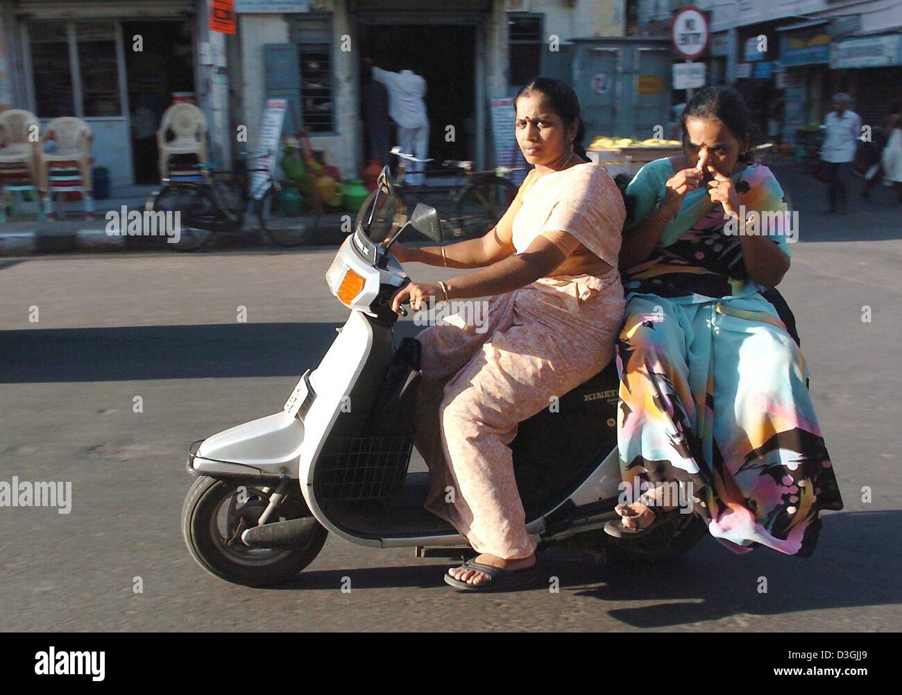 (Dpa) - fahren zwei Frauen auf einem Motorroller auf einer Straße in Chennai, früher bekannt als Madras, Indien, 21. Juli 2004. Kühe gelten als heilige Tiere in Indien. Die Stadt liegt im Süden von Indien wurde von den Portugiesen im 16. Jahrhundert gegründet. Chennai ist heute die viertgrößte Stadt in Indien mit 7 Millionen Einwohnern. Mehr als ein Viertel der Stadt Menschen leben in Slums Stockfoto