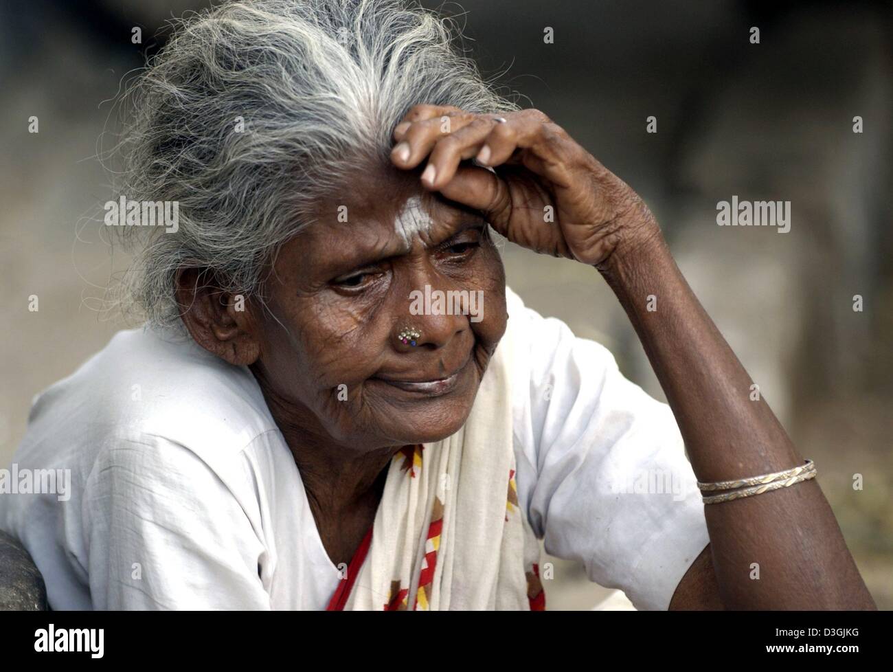 (Dpa) - eine Frau mit einem religiösen hinduistischen Schild an Stirn und Nase piercing sitzt auf einer Straße in Chennai, früher bekannt als Madras, Indien, 21. Juli 2004. Die Stadt liegt im Süden von Indien wurde von den Portugiesen im 16. Jahrhundert gegründet. Chennai ist heute die viertgrößte Stadt in Indien mit 7 Millionen Einwohnern. Mehr als ein Viertel der Stadt Menschen leben in Slums Stockfoto