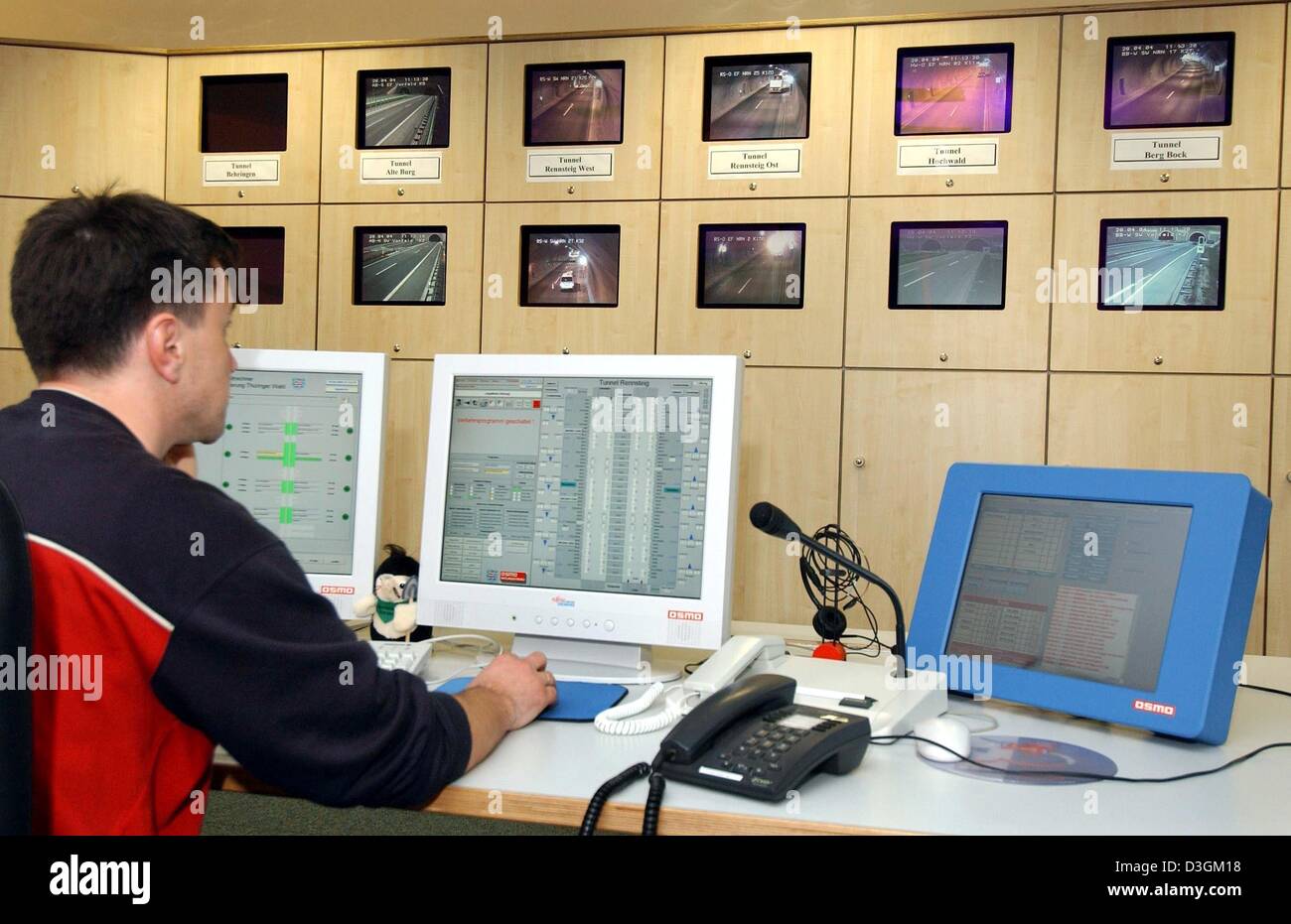 (Dpa) - ein Mann sitzt vor einem Computer-Bildschirm und überwacht die Einhaltung des Verkehrs fließen im OP-Saal der Rennsteig-Tunnel in der Nähe von Oberhof, Deutschland, 28. April 2004. Die 8 Kilometer lange Tunnel gewann die Europäische Sicherheitstest von dem deutschen Automobilclub ADAC, die insgesamt 27 Tunnel in neun europäischen Ländern enthalten. Stockfoto