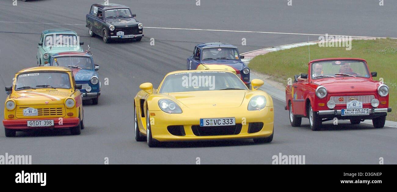 (Dpa) - A Porsche Carrera GT (C) mit 612 PS führt das Feld der Trabis während der 5. Trabirallye auf dem Testgelände der Porsche Werk in Leipzig, Deutschland, 17. Juni 2004. Rund 54 Trabis, ehemalige deutsche Automarke, beteiligte sich an einer Rallye feiert 100 Jahre Auto Designlösungen im Freistaat Sachsen und Rennen gegen Porsche Carrera GT. Stockfoto