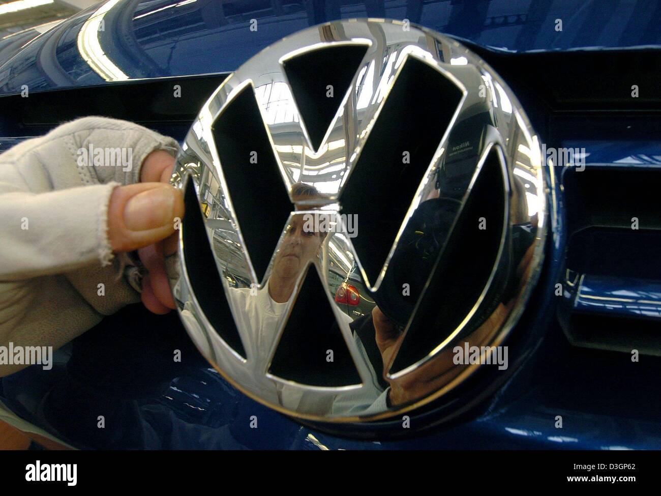 (Dpa) - eine Hand legt das VW-Logo auf dem Grill eine Entfernung V im Werk von Volkswagen in Wolfsburg, Deutschland am 24. Februar 2004. VW, Europas größter Automobilhersteller während einer Pressekonferenz am Dienstag, 9. März 2004 angekündigt, dass das Unternehmen seine rettende Politik angesichts der schlechten Wirtschaftslage anziehen wird.  Bernd Pischetsrieder, Vorstandsvorsitzender von Volkswagen, sagte t Stockfoto