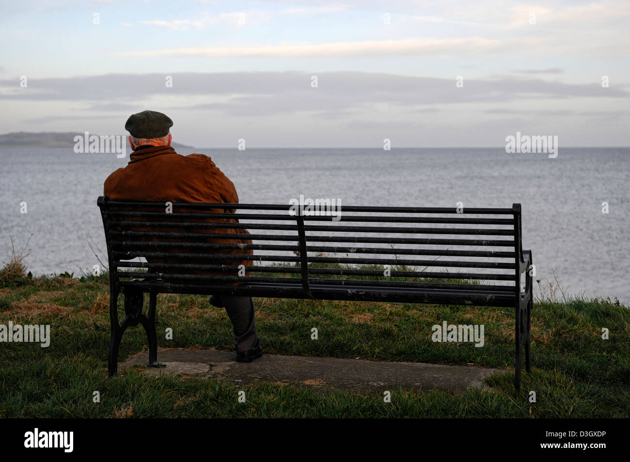 allein auf eigenen Sit Bank Blick auf Meer Ozean sitzen alte älterer Mann einsamer Single denken betrachten in Erinnerungen schwelgen Abends Sonnenuntergang Winter Stockfoto