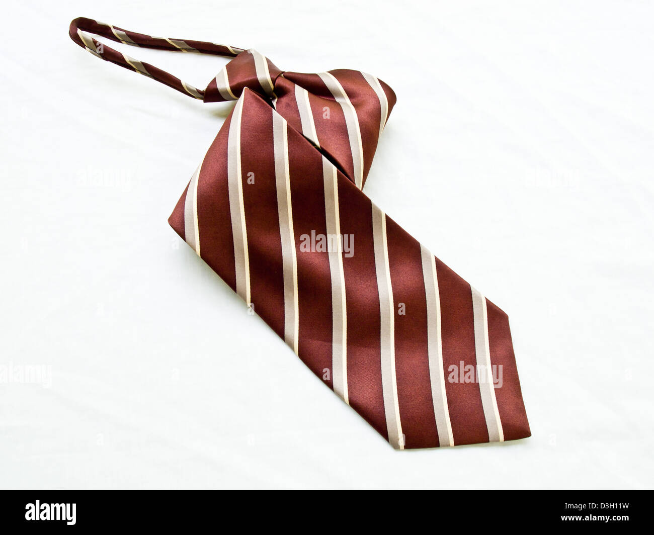 A aufgerollt gestreifte braune und weiße Krawatte isoliert auf weißem Hintergrund. Stockfoto
