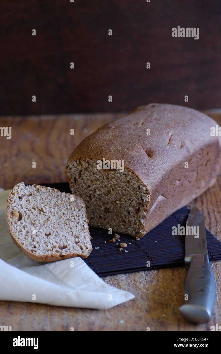 Handwerker-Brot, Weizenbrot Laib auf Holz Schneidebrett mit Brot Messer Scheibe Brot, Vollkornbrot mit weißen Stoffserviette Stockfoto