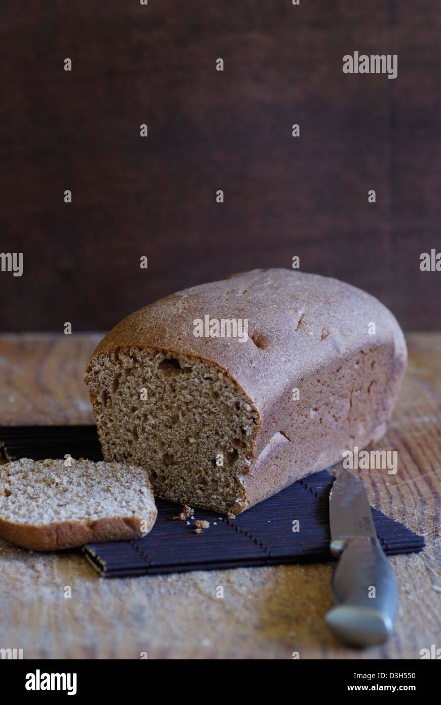 Artisan Brot, ganze Wheat Bread Loaf auf Holz Schneidebrett mit Messer, Schneiden des Brotes Stockfoto
