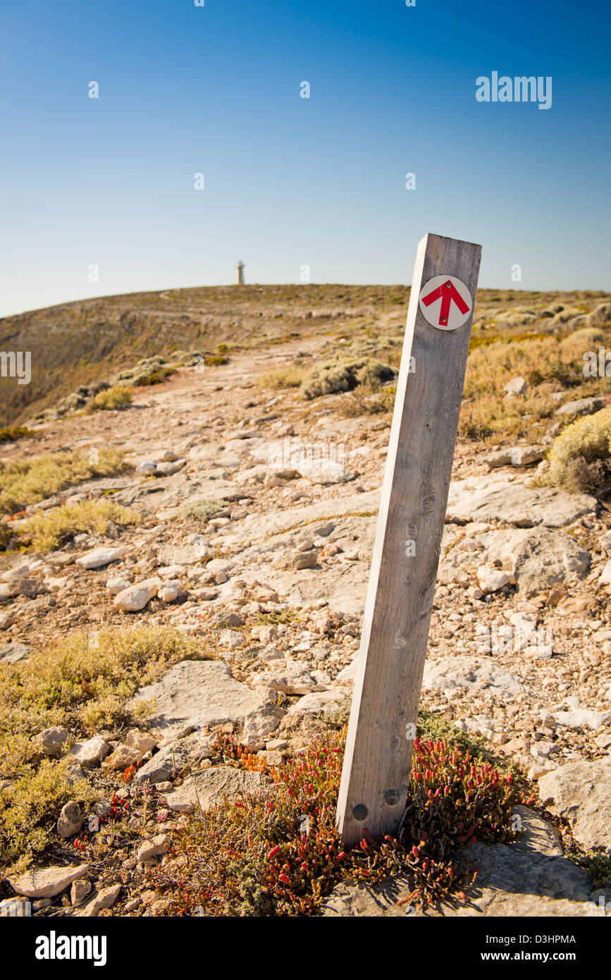 Pfeil auf Wegweiser zeigt die Richtung an den Klippen entlang zum fernen Leuchtturm Stockfoto