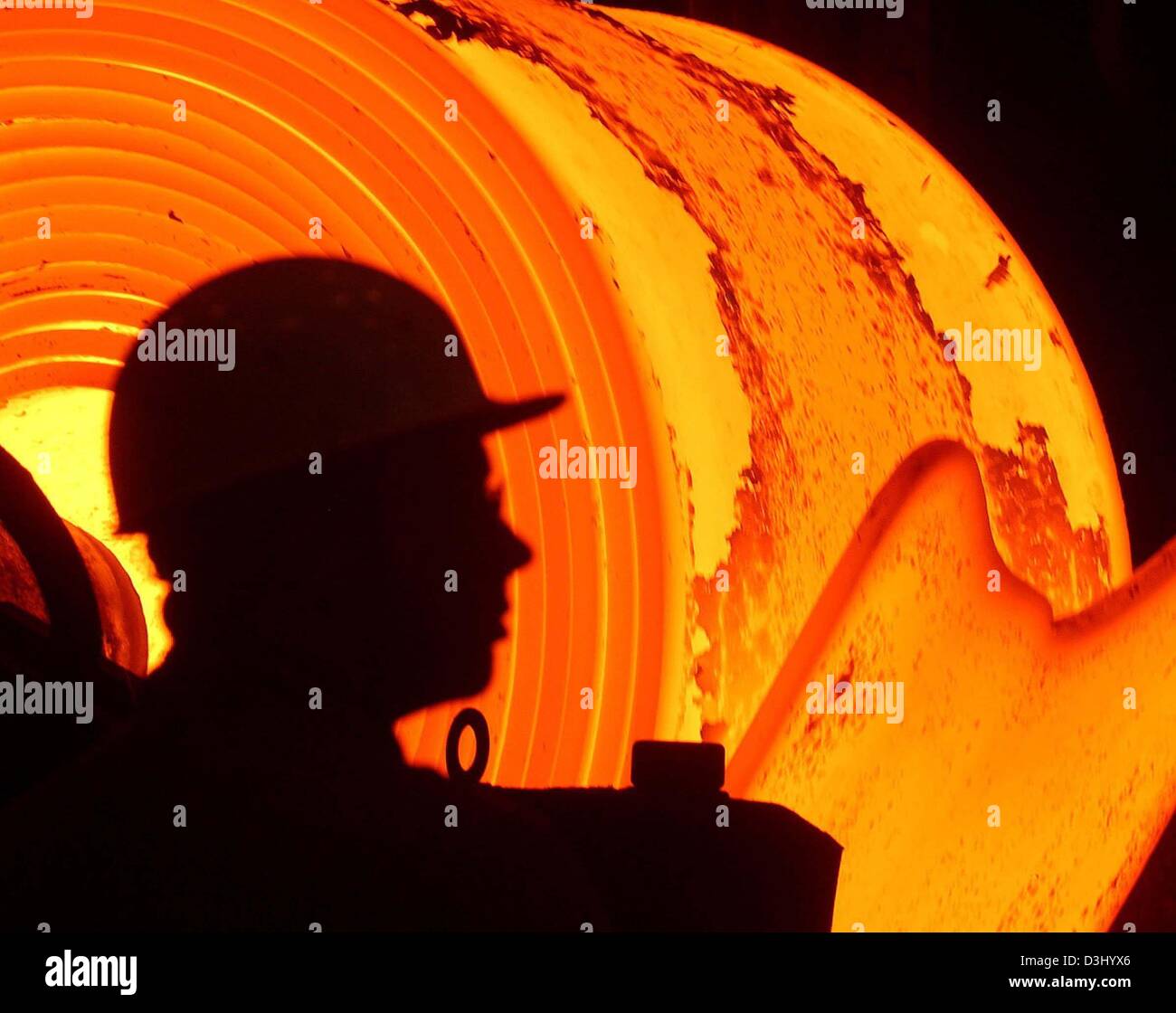 (Dpa-Dateien) - ist die Silhouette des ein Stahlarbeiter vor einem Redhot gesehen, über 1200 Grad Celsius heißen Stahl-Coils im ThyssenKrupp-Stahlwerk in Bochum, Deutschland, 12. Februar 2003. Am 23. Januar 2004 bestätigt ThyssenKrupp ihr Ziel, ein Bruttoergebnis von knapp 1 Milliarde Euro im laufenden Geschäftsjahr 2003/2004 zu erreichen. Das Unternehmen kündigte auch die Eckdaten für die Tannen Stockfoto