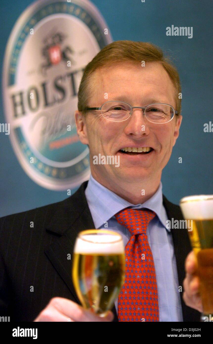 (Dpa) - Vorsitzender des Arbeitskreises dänischen Brauerei Carlsberg Nils S. Andersen steht vor einem Werbeplakat Holsten und hält ein Glas Bier in der Hand in Hamburg, Deutschland, 20. Januar 2004. Carlsberg übernimmt und Deutschlands zweitgrößte Brauerei Unternehmen Holsten bricht. Nach der vereinbarten Übernahme von 51 Prozent der Aktien von Holsten Carlsberg nun auf dem Holsten b verkaufen will Stockfoto