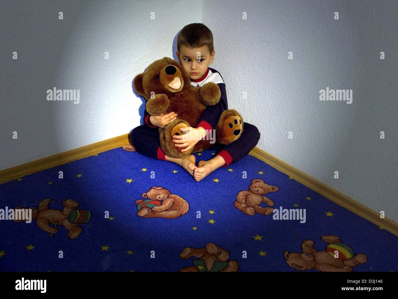 (Dpa) - ein Angst kleiner Junge hält seinen Teddy sitzend in einer Ecke seines Zimmers, in einer inszenierten Szene in Frankfurt Oder, Deutschland, 15. Januar 2004. Laut Ärzten steigt die Gewalt gegen Kinder. Die Zahl von missbrauchten Kindern steigt in deutschen Krankenhäusern mit Gewalt in allen gesellschaftlichen Bereichen. Stockfoto