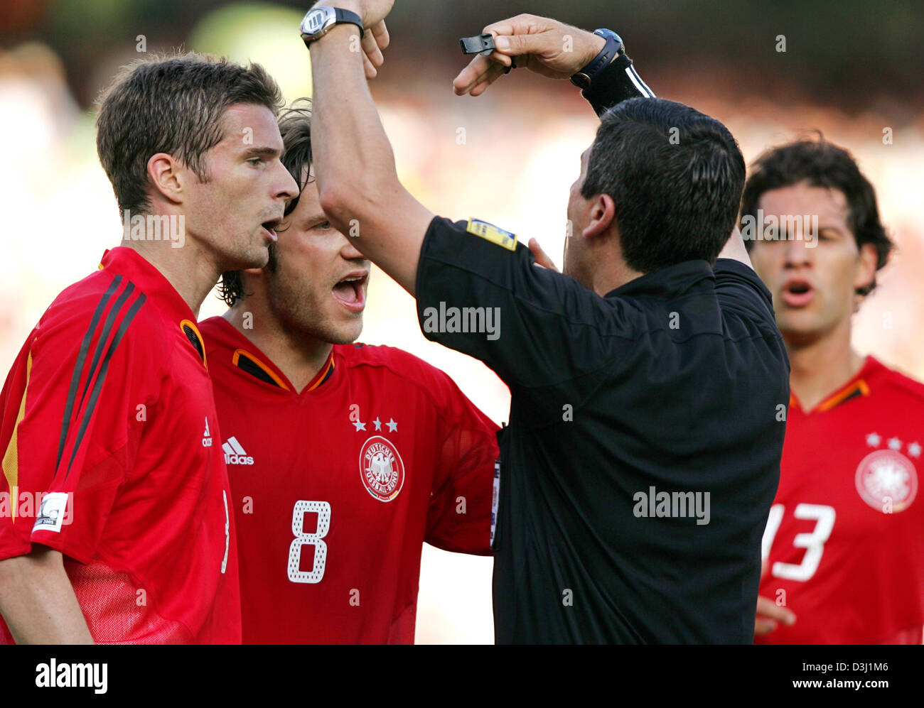 (Dpa) - diskutieren deutsche Fußballer Arne Friedrich (von L bis R), Torsten Frings und Michael Ballack mit Schiedsrichter Carlos Chandia während das Halbfinale des FIFA Konföderationen-Pokal-Turnier Deutschland vs. Brasilien in Nürnberg, 25. Juni 2005. Stockfoto