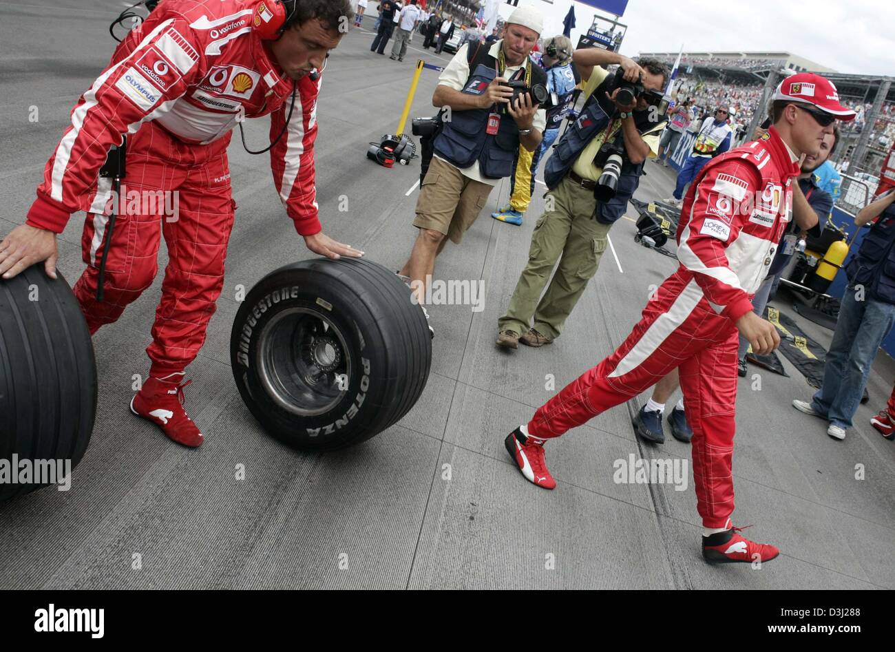 (Dpa) - das Bild zeigt deutsche Formel1 Fahrer Michael Schumacher (R) von Ferrari und ein Mechaniker mit Bridgestone-Reifen (L) vor dem Start zum Grand Prix in Indianapolis, USA, 19. Juni 2005. Der Grand Prix vorgestellten nur sechs Autos, weil alle sieben Teams, die mit Michelin-Reifen ausgestattet zog sich aus dem Rennen wegen Sicherheitsbedenken. Stockfoto