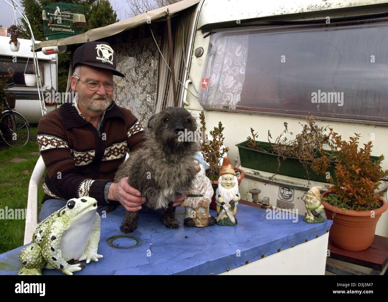 (Dpa) - permanente Wohnmobil Manfred Pletzer mit seinem Terrier Iggy sitzt vor seinem Wohnwagen auf einem Campingplatz in Hameln, Deutschland, 16. Dezember 2003. Das 60-Jahr-alte lebt seit 30 Jahren in seinem Wohnwagen, davon 20 Jahre auf dem Campingplatz "Zum Faehrhaus" in Hameln. Der Campingplatz ist seine offizielle Residenz, und die Adresse auf seinem Ausweis. Seine weiterführenden Stockfoto