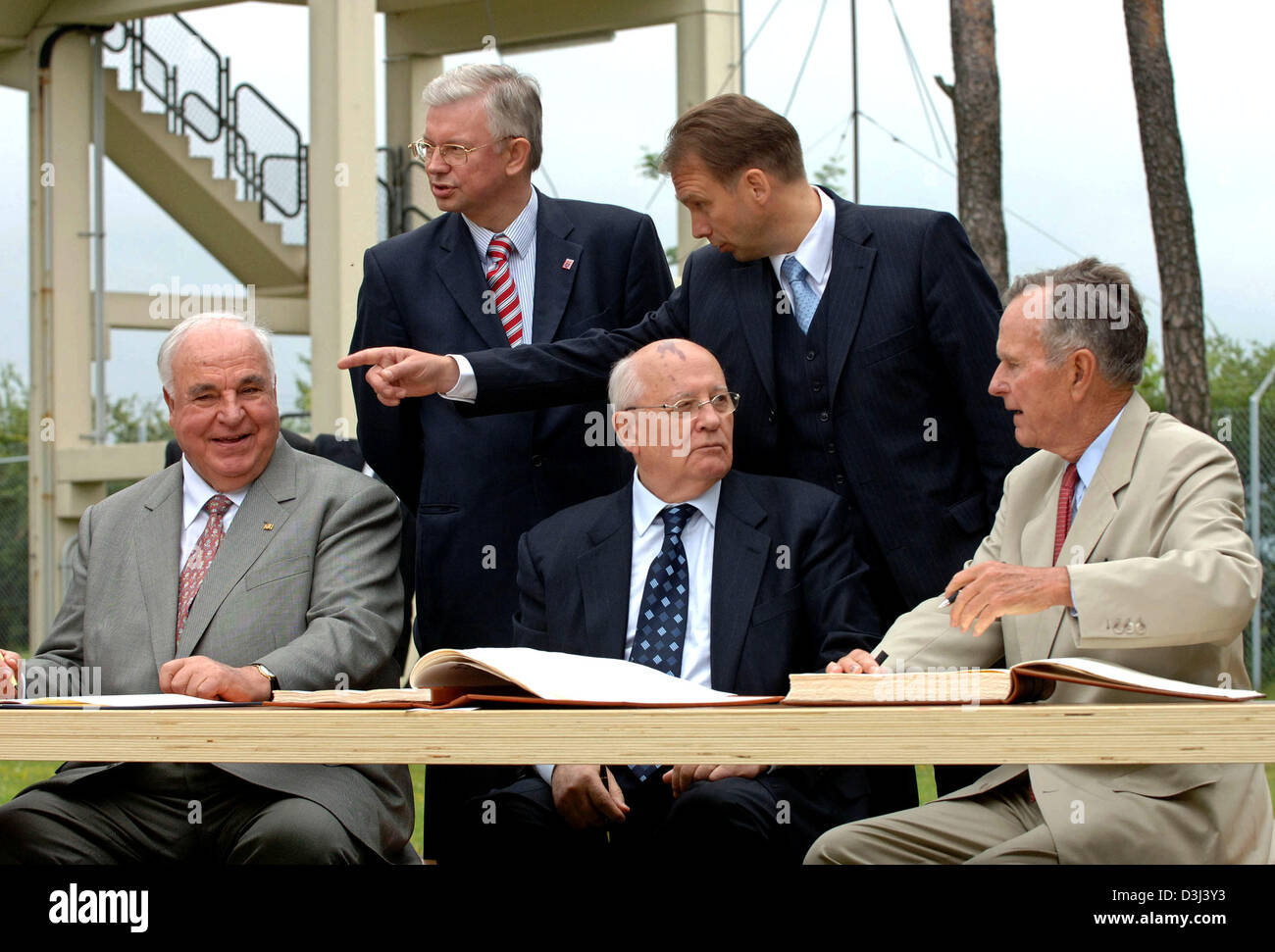 Der ehemalige deutsche Bundeskanzler Helmut Kohl (L), in der Nähe von ehemaligen Soviet Union President Mikhail Gorbachev (C) und ehemalige U.S. President George Bush (R) Zeichen das Gästebuch der Ära des Kalten Krieges US Army Beobachtungsposten "Point Alpha" an der Demarkationslinie zwischen Ost- und Westdeutschland Dorf Geisa, Deutschland, 17. Juni 2005. Das Bild zeigt im Hintergrund die konservative Premierminister Stockfoto