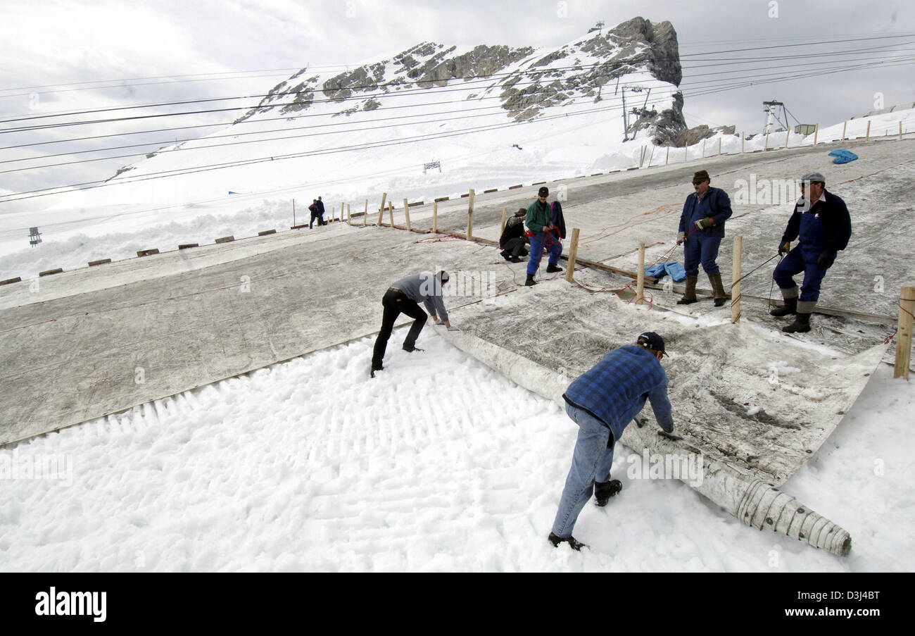 (Dpa) - Arbeiter legen großen Leinwand auf dem ca. 2.700 Meter hohen Zugspitz-Gletscher mit der Hand auf der Zugspitze, Deutschland, Dienstag, 14. Juni 2005. Insgesamt ca. 6.000 m ² Matten und Leinwand wird auf das "ewige Eis" gelegt. Das Material reflektiert das Sonnenlicht und schützt vor warmer Regen vor allem im Sommer. Jede Canva ist fünf Meter breit und 30 Meter lang. Durch diese Aktion Stockfoto