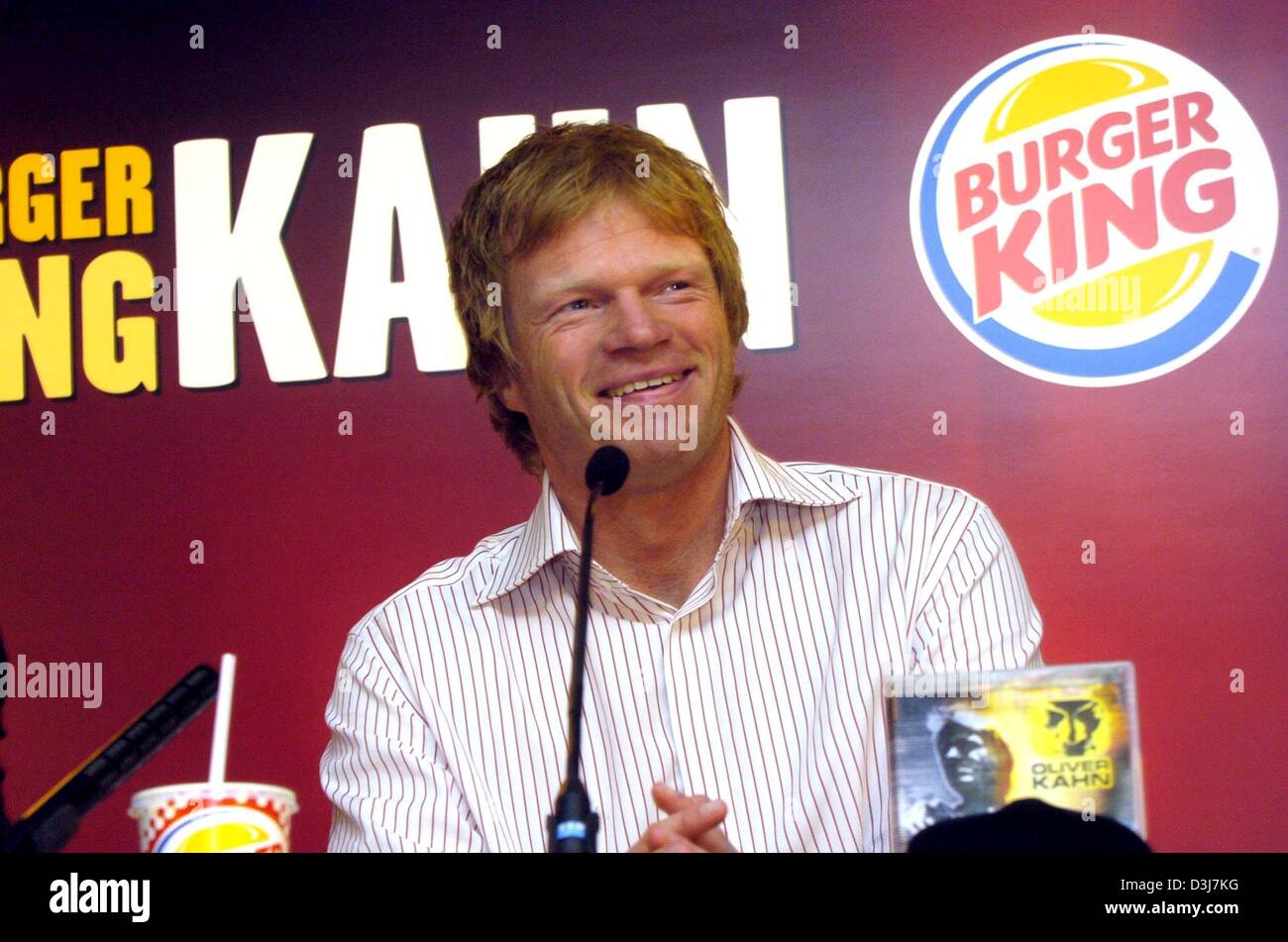 (Dpa) - Bayern München Torwart Oliver Kahn lächelt, als er während einer Pressekonferenz in München, Deutschland, 18. Mai 2004 vor dem Logo von der Fastfood-Kette Burger King sitzt. Ab 1 Juni wird Kahn werben Burger King für die folgenden zwei Monate um die Fußball-Europameisterschaft in Portugal zu begleiten. Er schlug auch einen Deal um seine persönliche Fan-Zugang zu verteilen Stockfoto