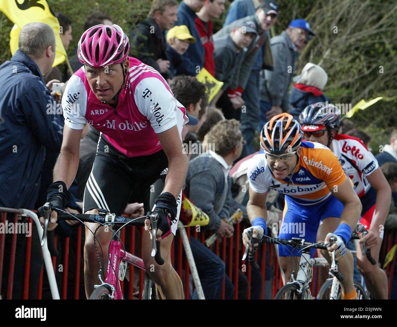 (Dpa) - deutsche Radfahrer Jan Schaffrath (L) von T-Mobile Team reitet auf seinem Fahrrad bergauf, dicht gefolgt von niederländischen Radrennfahrer Steven de Jongh von Team Rabobank, vorbei an einer jubelnden Menge von Zuschauern bei der Flandern-Rundfahrt, das zweite Rennen der World Cup Serie, in der Nähe von Meerbecke, Belgien, 4. April 2004. Das Rennen umfasst eine Strecke von 257 km. Stockfoto