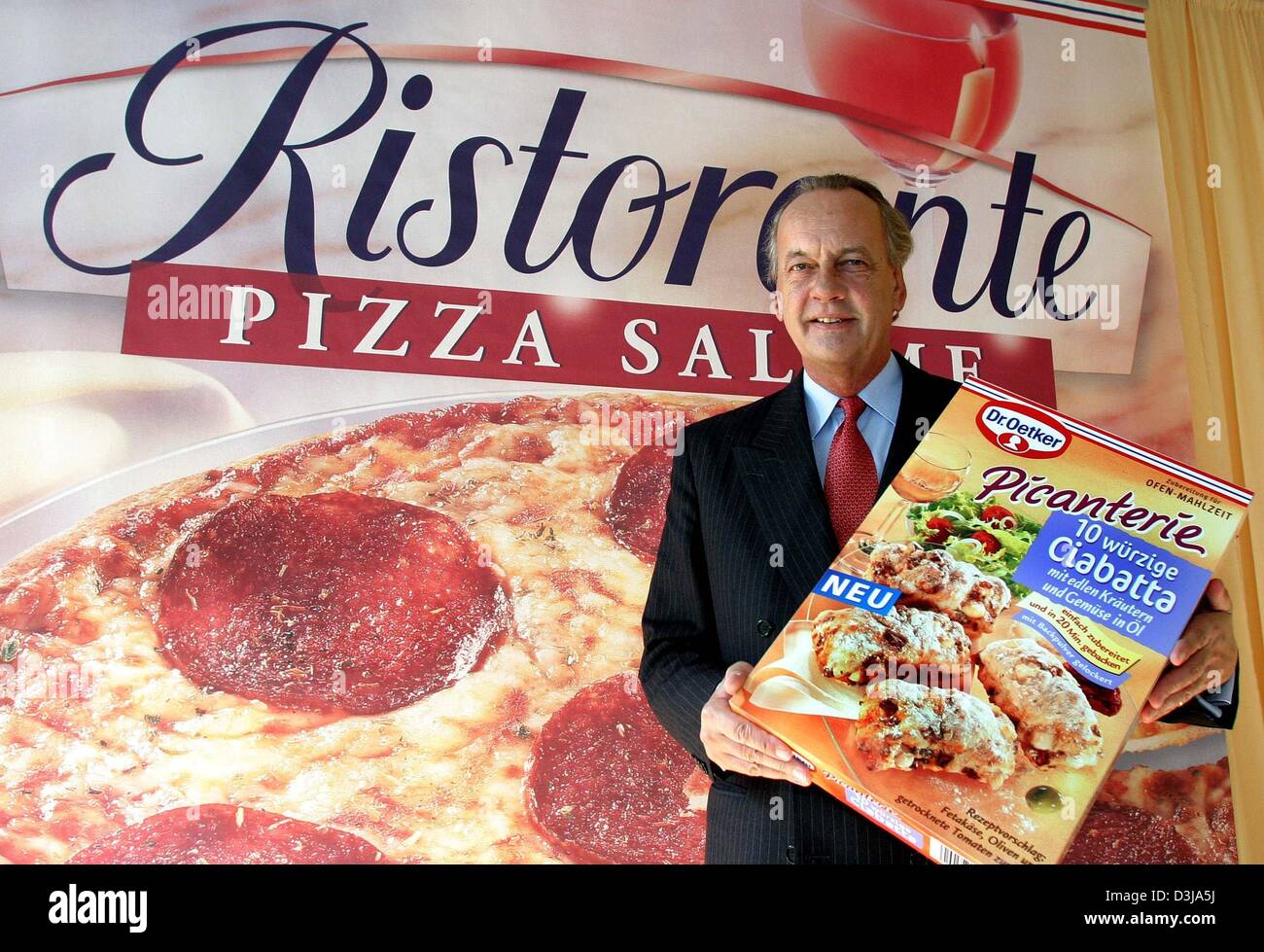 (Dpa) - Dr. August Oetker, Vorsitzender des Vorstands der Dr. Oetker International GmbH-Food-Hersteller, präsentiert das Werbeplakat für eine Tiefkühlpizza in Bielefeld, Deutschland 30. März 2004. Das Unternehmen kündigte auf der Jahrespressekonferenz Bilanz einen Umsatz auf 1,12 Milliarden Euro, der ein Plus von 5,6 Prozent widerspiegelt. Stockfoto