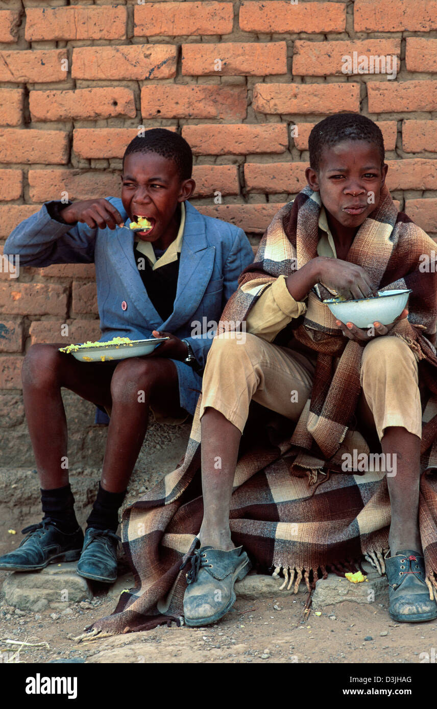 Schuljungen essen ihr kostenloses Mittagessen auf dem Schulhof, Matsieng, Lesotho Stockfoto