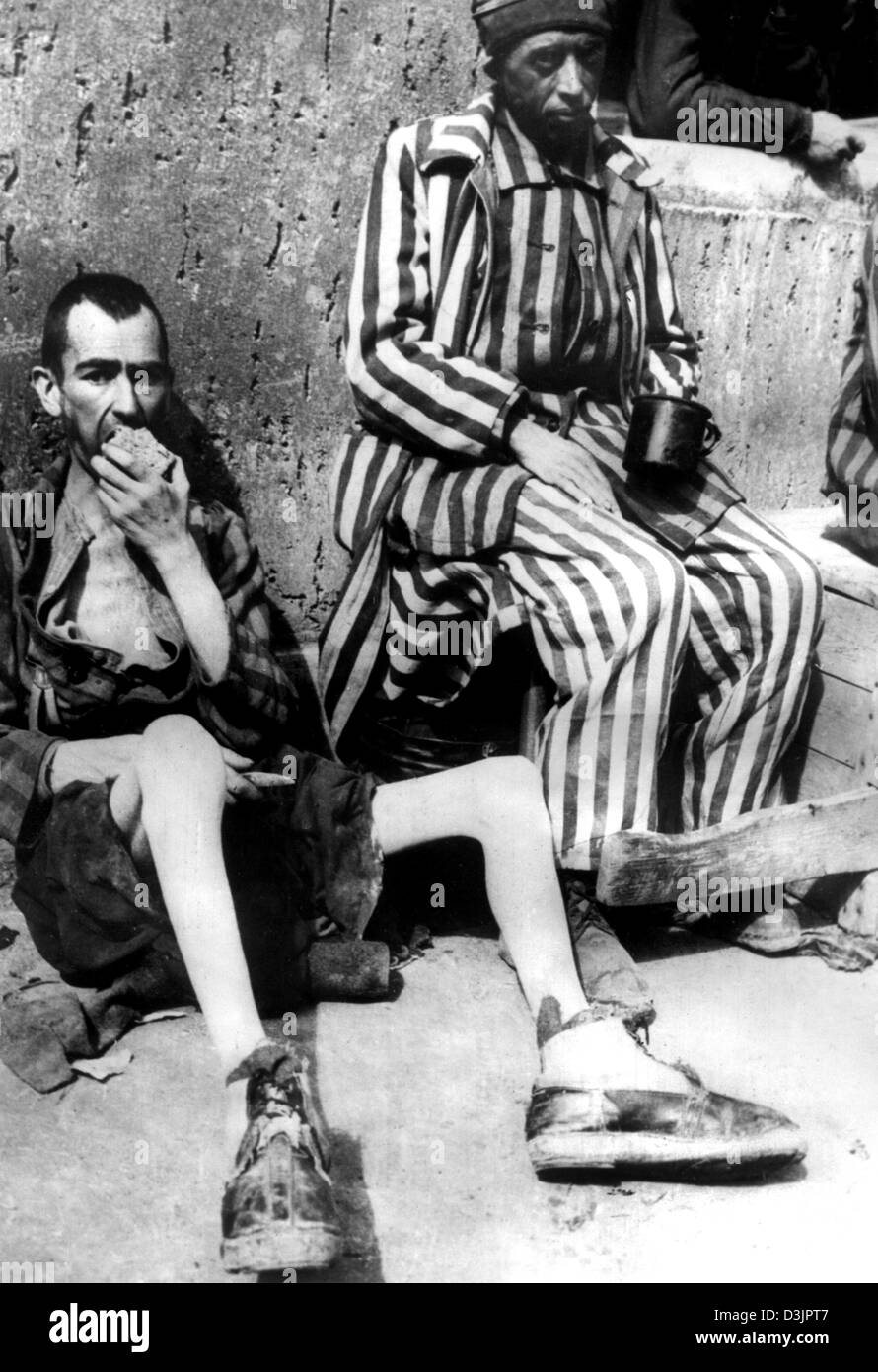 (Dpa-Dateien) - lehnen zwei ausgemergelten Fromer Gefangenen gegen eine Wand während des Essens eines Laib Brot nach der Befreiung des Konzentrationslagers Buchenwald von der 3. US-Armee in Buchenwald, Deutschland, 13. April 1945. Stockfoto