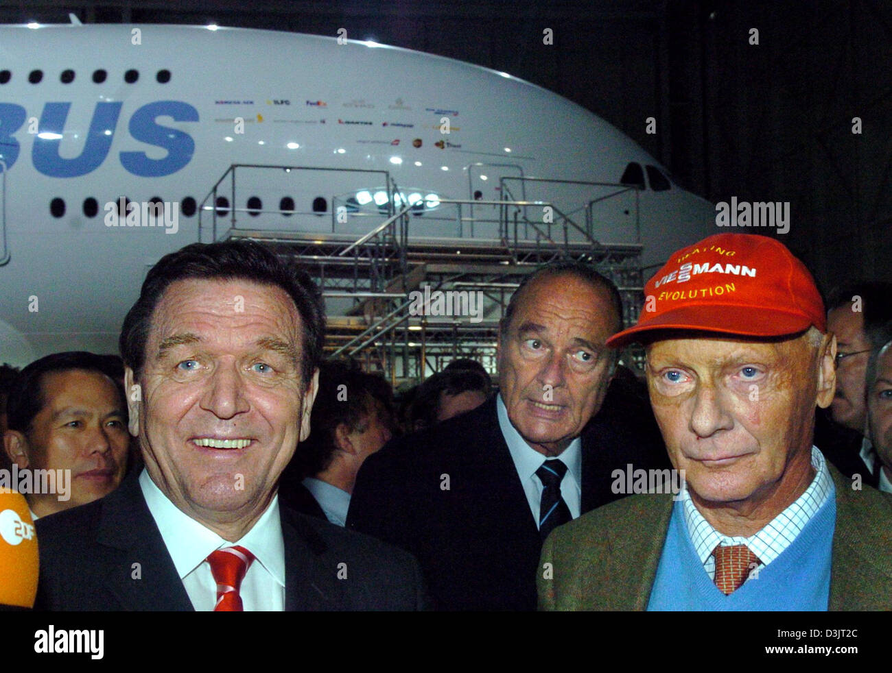 (Dpa) - steht er neben ehemaligen Formel 1 WM Weltmeister lächelt der deutsche Bundeskanzler Gerhard Schröder (L) Niki Lauda (R) während French President Jacques Chirac (C) hinter ihnen steht, nach der Enthüllung des neuen Airbus A380 Superjumbo (wieder) am Produktionsstandort in Toulouse, Frankreich, Dienstag, 18. Januar 2005. Die standard-Version des weltweit größten jemals gebauten Passagiers ein Stockfoto