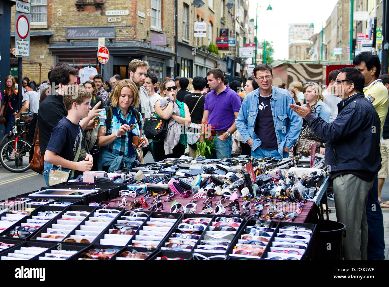 Familie Feilschen um Sonnenbrillen mit Markt-Stall-Inhaber auf der Brick Lane Stockfoto