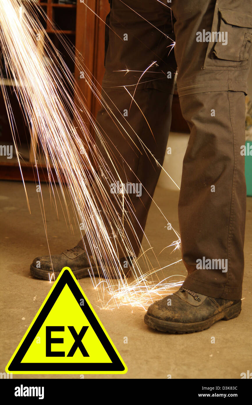 Füße eines Arbeitnehmers mit Funken einem Winkelschleifer und ein Zeichen Stockfoto