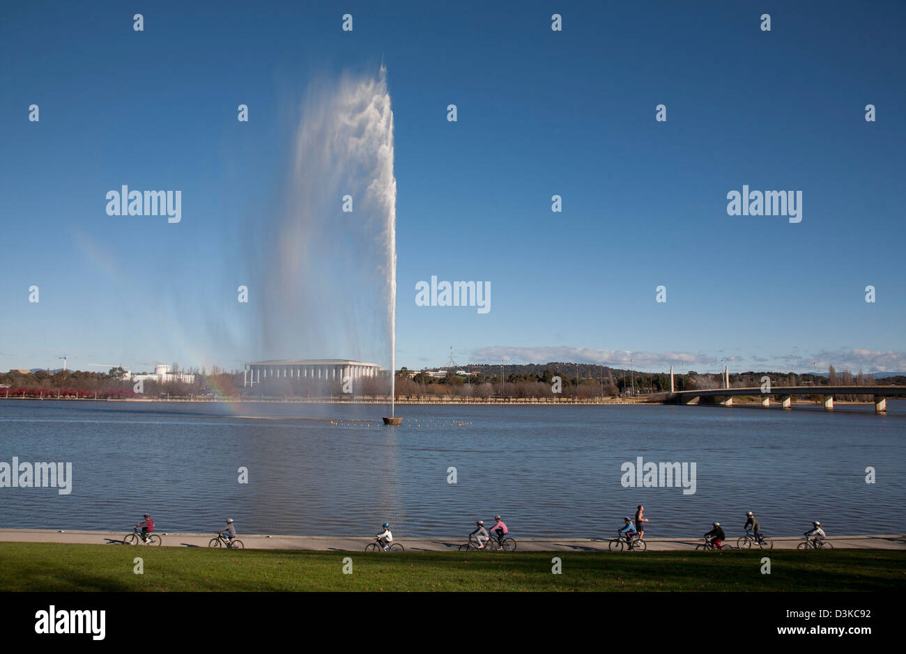 Gruppe von Schulkindern Radfahren entlang Lake Burley Griffin mit Captain Cook Memorial Jet Canberra Australien bereisen Stockfoto