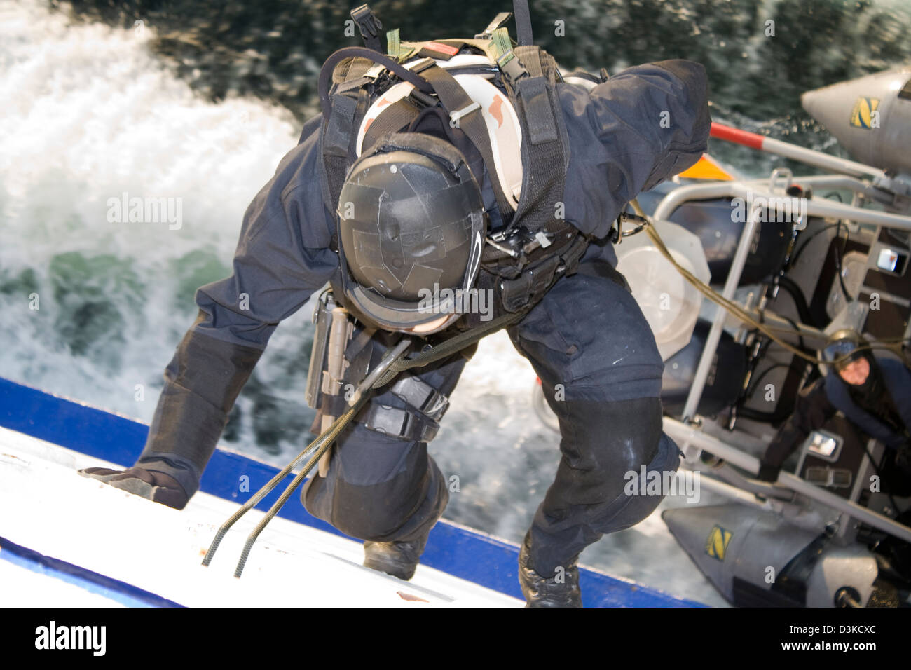 Ein Spezialeinheit (SWAT) Agent stößt auf der Seite von einem beweglichen Schiff ein Begleitboot. Stockfoto