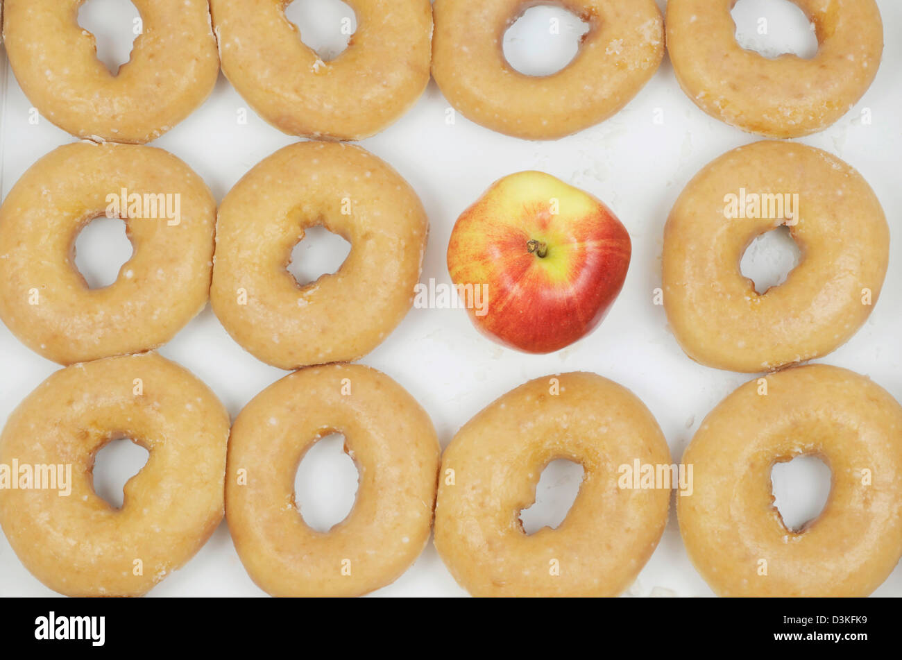 Elf Donuts abgebildet mit einem Apfel ersetzen, was ein Dutzend Donuts in einem Kasten, alle Schuss von oben gemacht hätte. Stockfoto