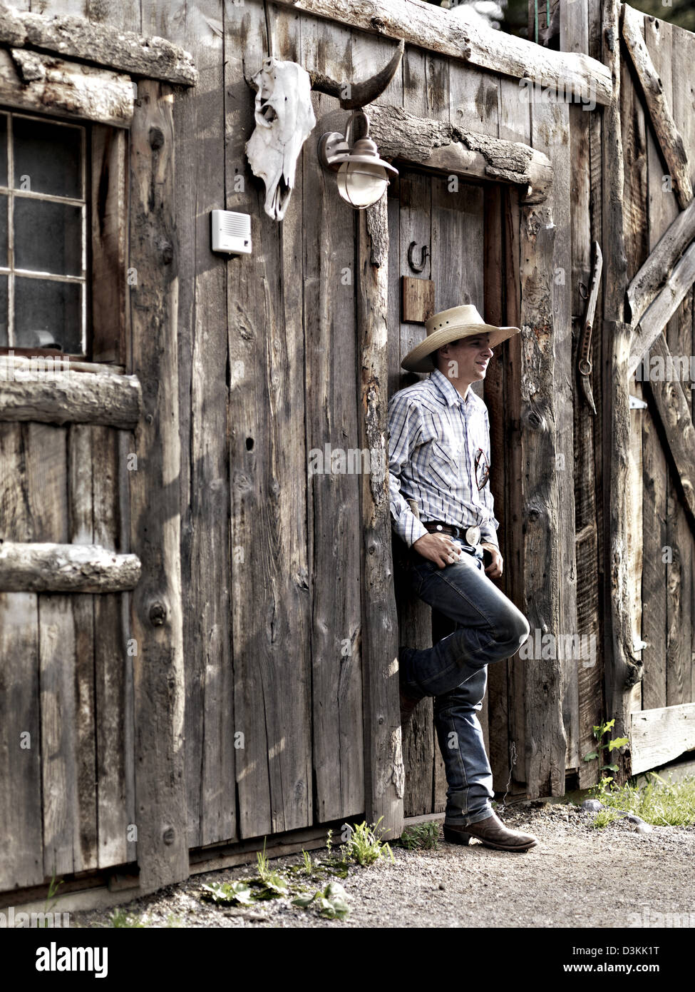 Cowboy steht an Außenseite der Blockhütte, Montana, USA Stockfoto