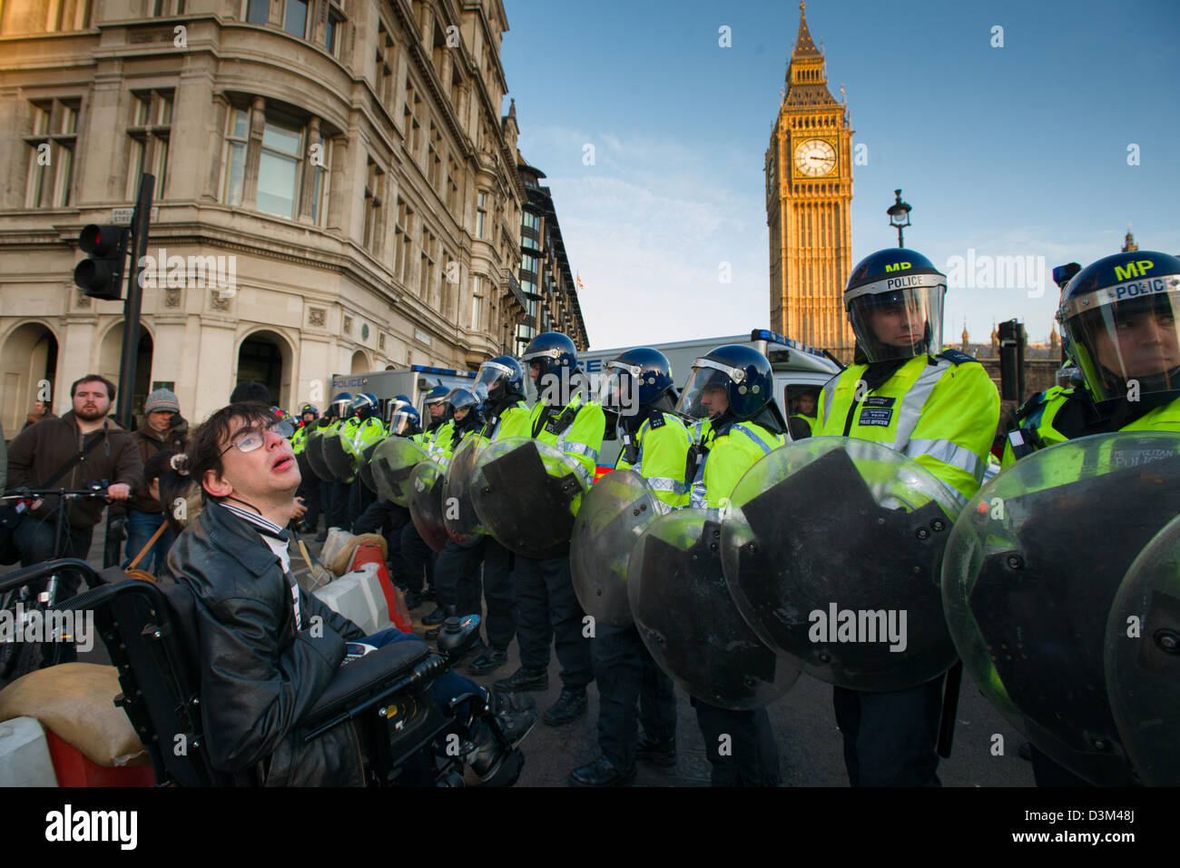Behinderte Menschen in einem Rollstuhl, die Konfrontation mit einer Polizeiabsperrung in voller Kampfausrüstung vor der Houses of Parliament, Tag X3 Studentendemonstration, London, England Stockfoto