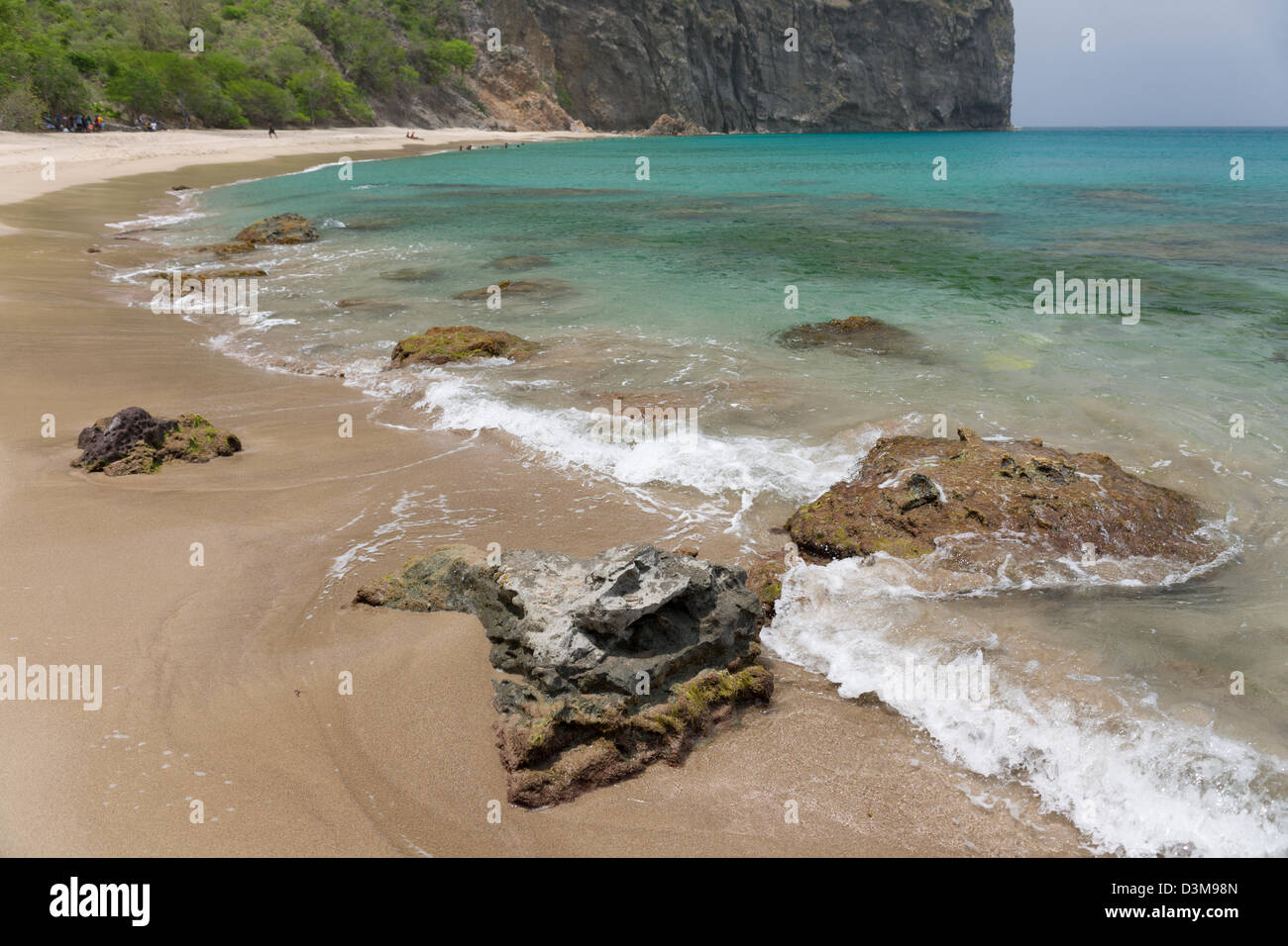 Wellen brechen über vulkanische Felsen am sandigen Strand von Rendezvous Bay, Montserrat Stockfoto