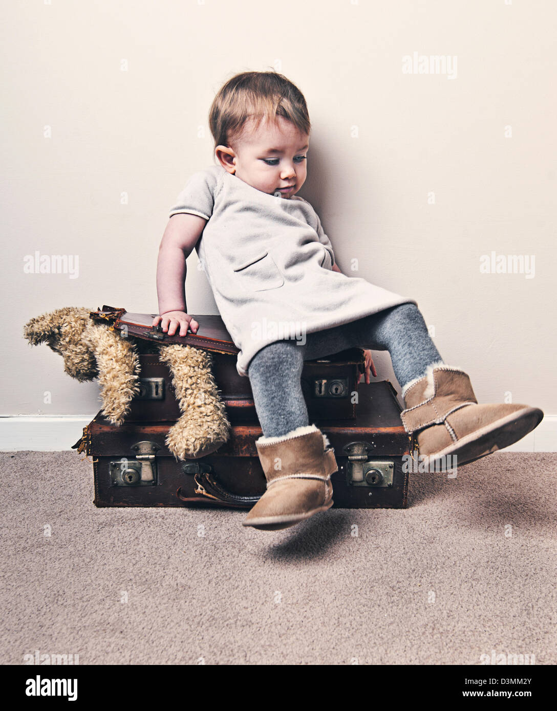 Babymädchen sitzen auf Koffer zu quetschen Teddy In Stockfoto