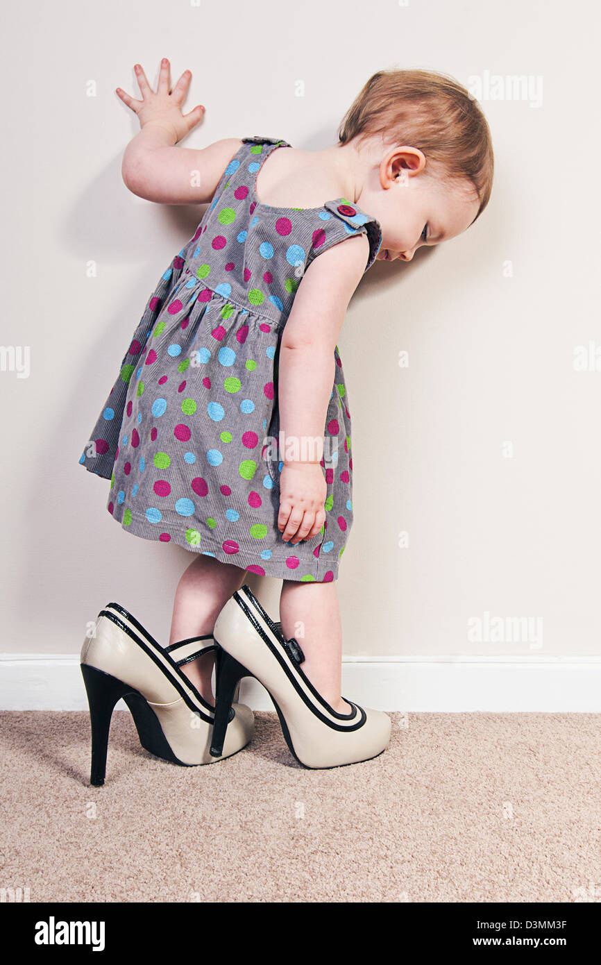 Babymädchen versucht auf Mutters High Heels Stockfoto