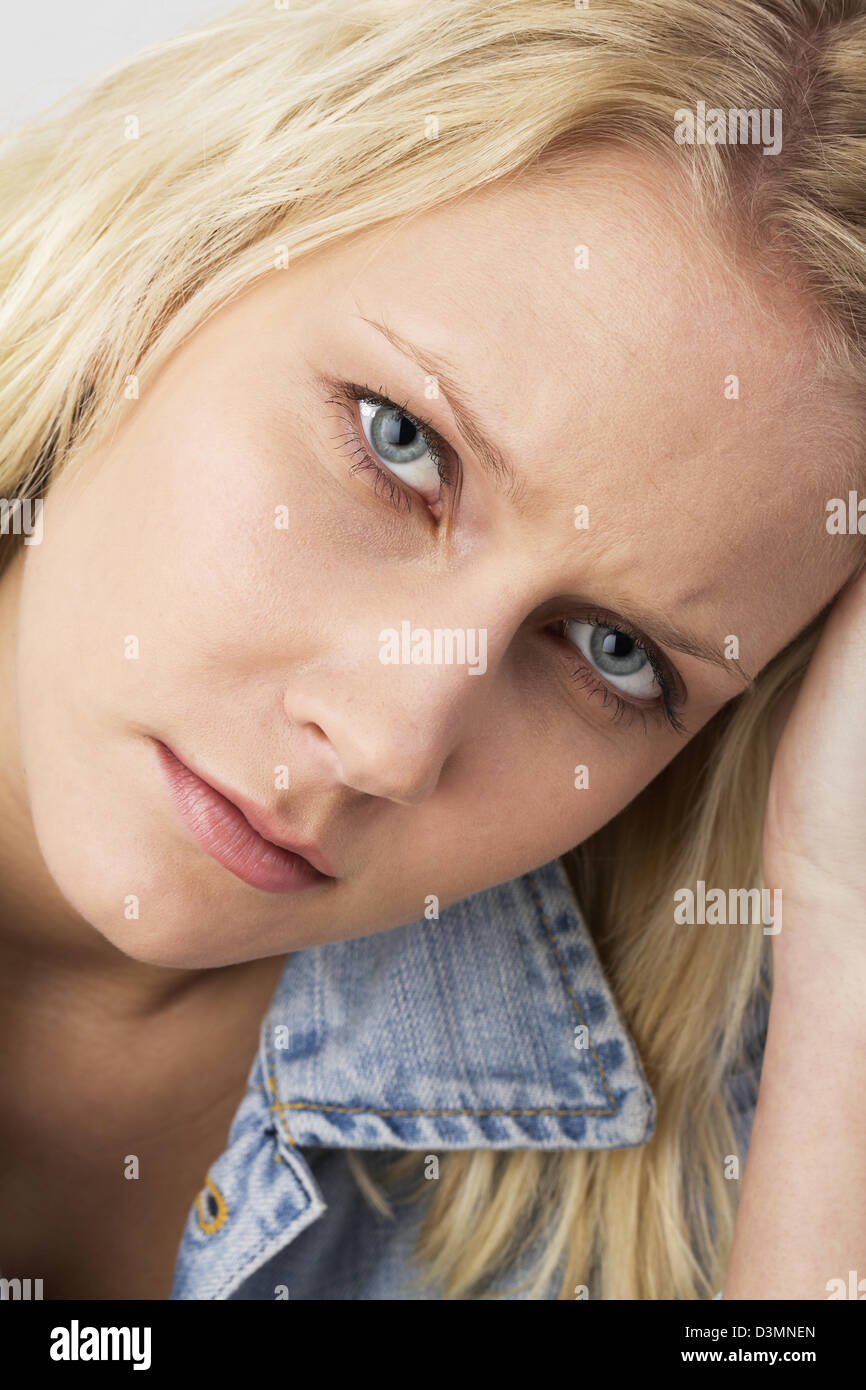 Porträt einer traurigen blonden jungen Frau schaut nachdenklich in die Kamera hielt ihre Hand auf den Kopf. Studio schossen so nah Stockfoto
