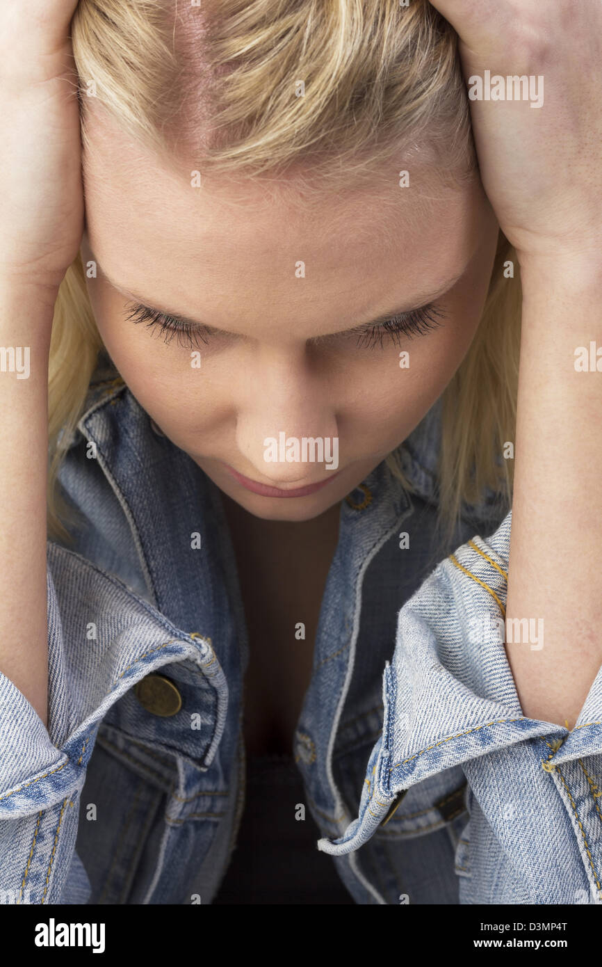 Porträt einer traurigen blonden jungen Frau blickte nachdenklich halten ihre Hände auf den Kopf. Nachdenklich Studio gedreht als Nahaufnahme Stockfoto