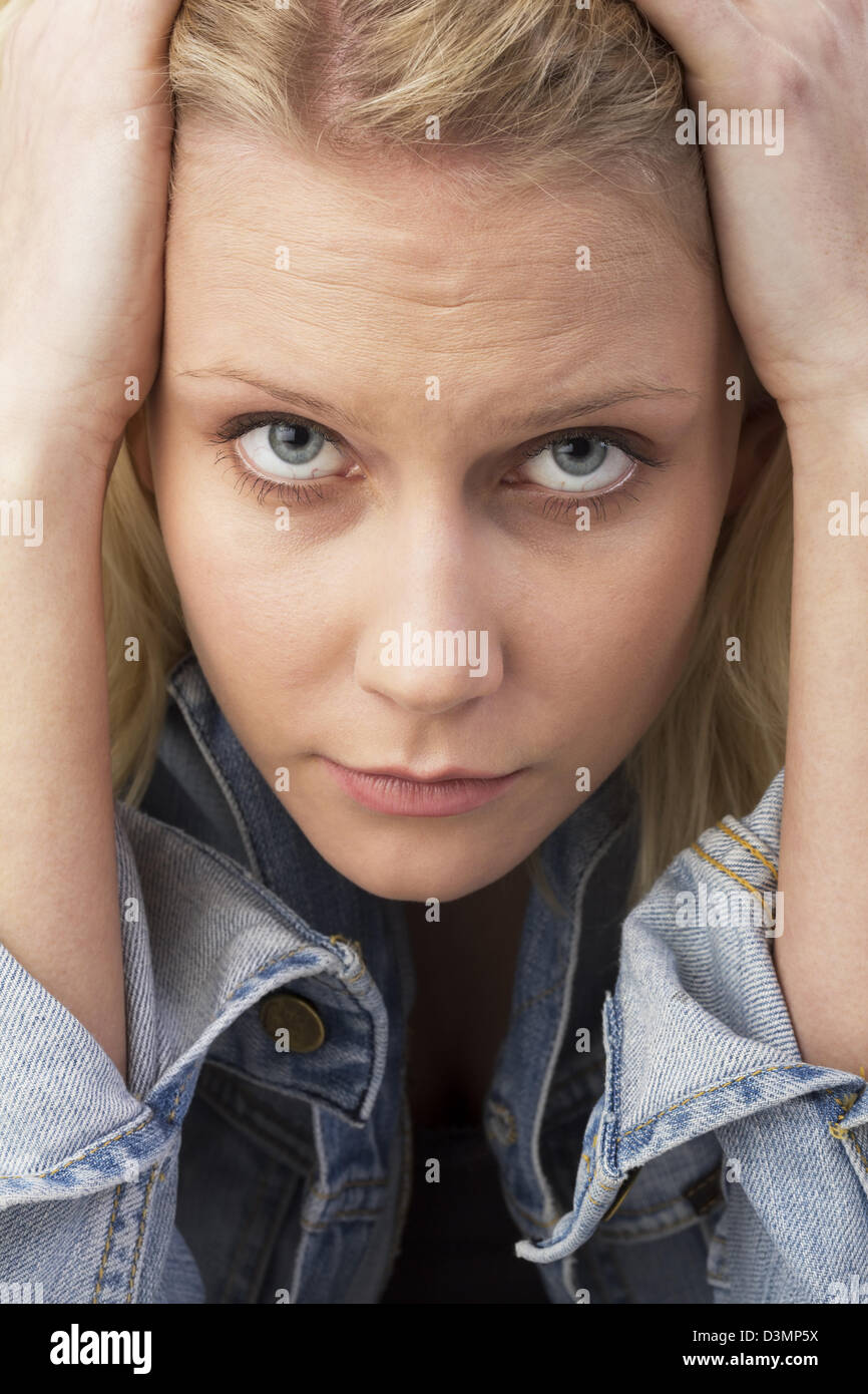 Porträt einer traurigen blonden jungen Frau schauen traurig in die Kamera halten ihre Hände auf den Kopf. Nachdenklich Studio gedreht als Nahaufnahme Stockfoto