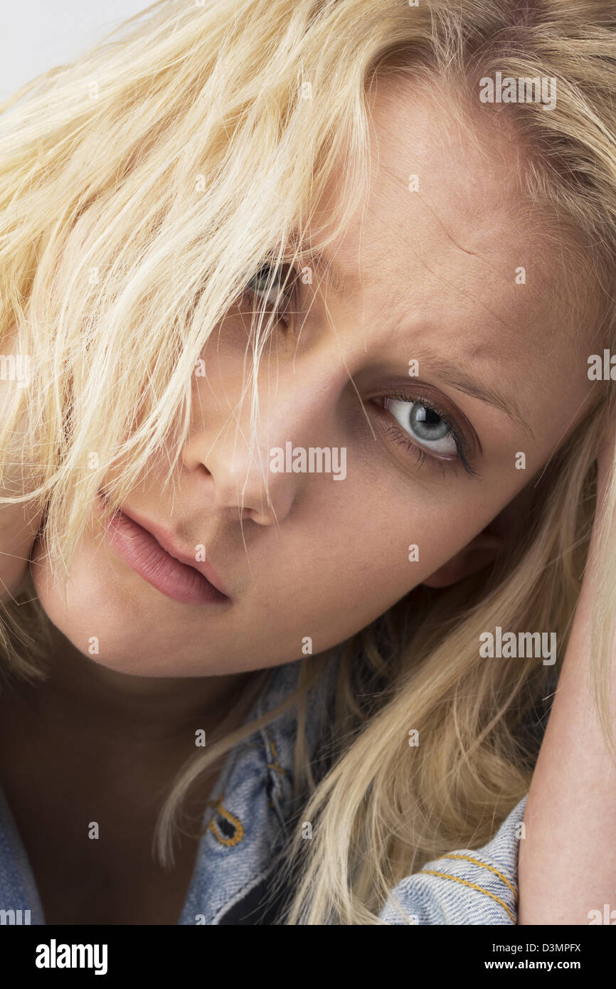 Porträt einer traurigen jungen Frau mit blonden zerzausten Haaren auf der verzweifelten Suche und hielt ihre Hand auf den Kopf. Studio als Closeup erschossen Stockfoto