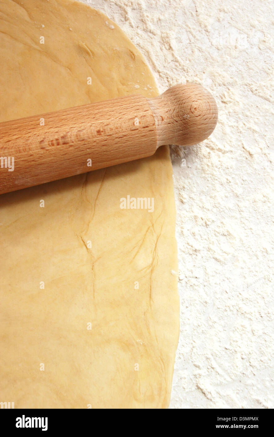 Portraitbild von frischen Teig auf einer bemehlten Arbeitsfläche mit einem hölzernen Nudelholz ausgerollt Stockfoto