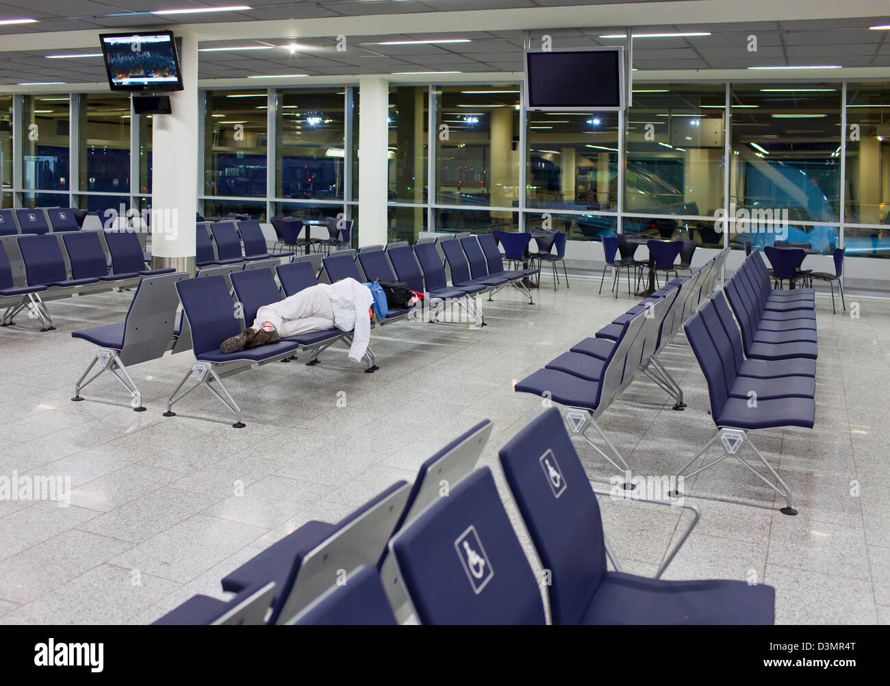 Passagier schläft auf sitzen in einem leeren Nacht Flughafen nach Annullierung des Fluges Stockfoto