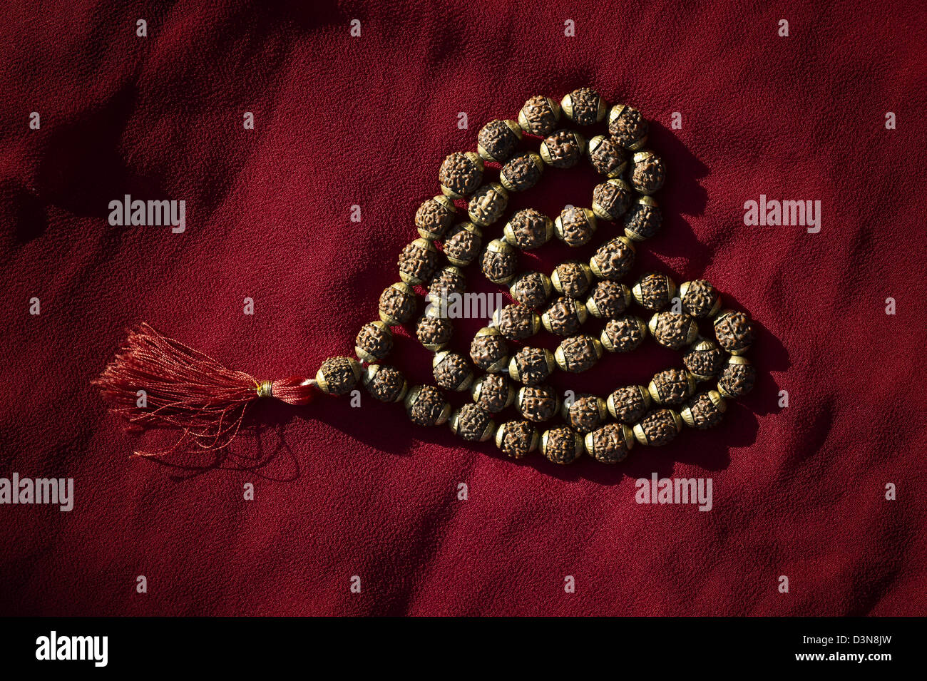 Rudraksha / Japa Mala Gebetskette in Herz Form auf rotem Stoff Stockfoto