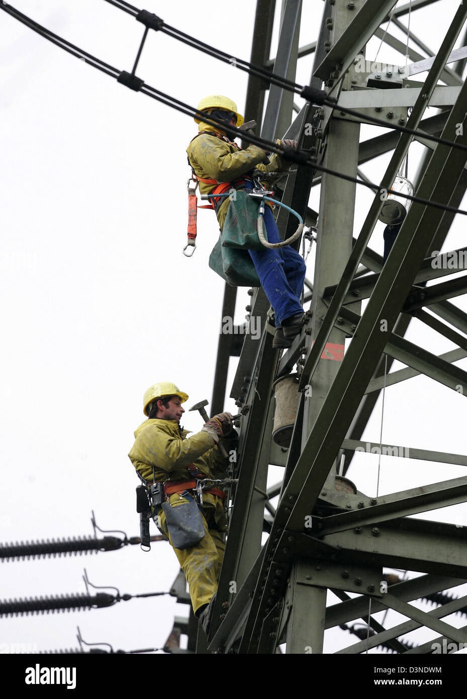 Arbeitnehmer erhalten eine Stromleitung während an einem Hochspannungsmast in Moers, Deutschland, 22. Februar 2006. Foto: Roland Weihrauch Stockfoto