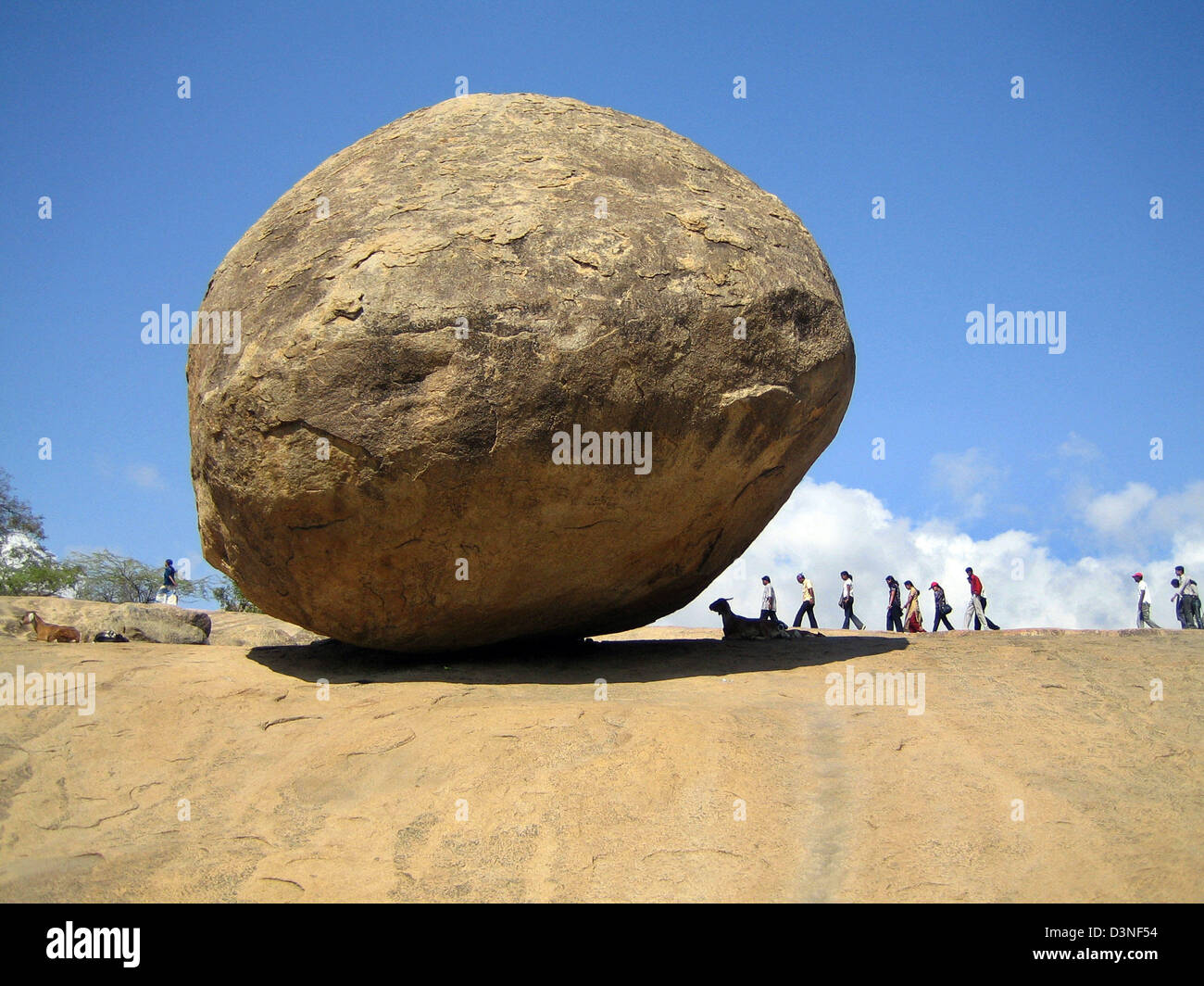 Touristen gehen vorbei an "Krishnas Butterball", einen massiven Felsen, die an einem Berghang befindet sich auf dem Gelände der Felsentempel, Mahabalipuram, im Bundesstaat Tamil Nadu, Indien, 4. März 2006 Haltung scheint. Die Sehenswürdigkeiten finden Sie hier sind ausgezeichnete Beispiele der Pallava Kunst und gehören vor allem Felsen-schneiden und monolithische Denkmäler und Reliefs. Sie bieten den ersten e Stockfoto