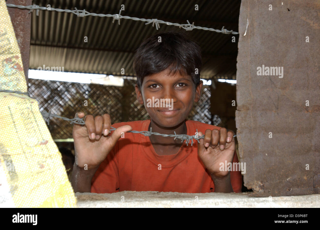 (Dpa-Datei) - das Bild zeigt einen jungen hinter einem Fenster mit Stacheldraht in einem abgelegenen Dorf in der Nähe von Chandrapur, Indien, 2. Juli 2006. Foto: Wolfgang Langenstrassen Stockfoto